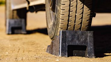 Tire stabilizer block supporting a vehicle tire on a dirt surface.