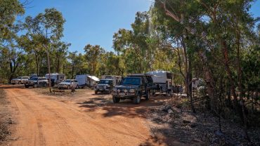 Remote camping area with campervans and trees in Australia.