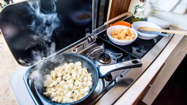 Portable campervan stove with tofu cooking and breakfast setup.