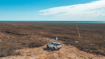 Outback road trip with a truck and traveler exploring remote Australian landscape.