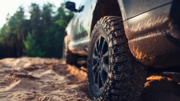 Off-road vehicle driving on rugged dirt trail in natural outdoor setting.