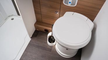 Compact RV bathroom with toilet and shower for travel comfort.
