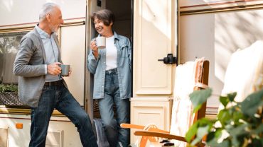 Two seniors sharing a coffee and conversation outside a caravan.