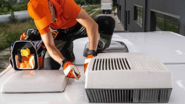 Technician repairing roof ventilation system on commercial building.