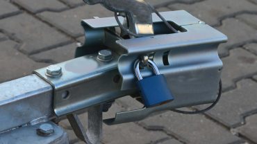 Trailer hitch with padlock on paved surface for secure towing.