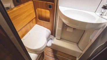 RV bathroom with toilet and sink in compact wooden space.