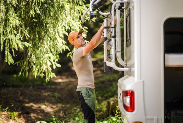 Camping van with outdoor gear and a woman preparing for adventure.
