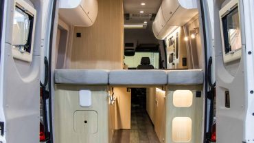 A compact campervan interior with custom storage, sleeping area, and modern amenities.