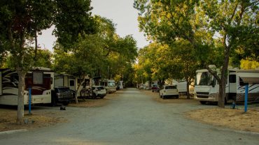 RV park entrance with parked caravans and trees in Australia.