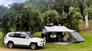 Campervan and tent setup in lush green outdoor camping area.