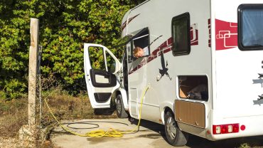 Electric campervan charging setup with solar panels and power outlet.