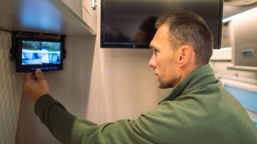 Man installing security camera inside a campervan or RV.