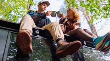Adventure couple enjoying coffee on a tree branch in nature.