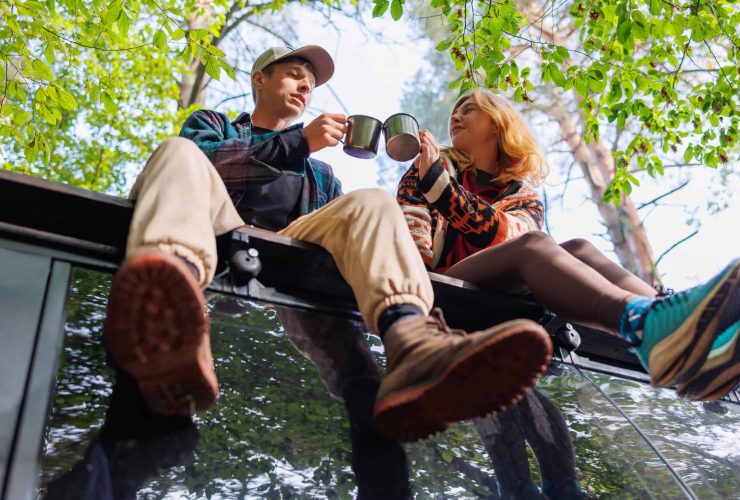 Adventure couple enjoying coffee on a tree branch in nature.