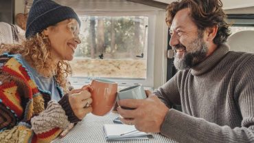Happy couple sharing coffee in a cozy campervan, enjoying travel and adventure.