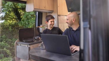 Camping with family in a campervan, using a laptop and enjoying quality time.