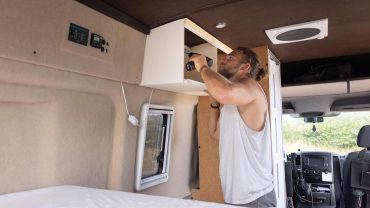 Man installing a device inside a campervan for travel adventures.