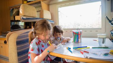 Children drawing and colouring inside a campervan.