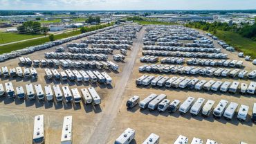 Large RV storage lot with numerous parked caravans and motorhomes.
