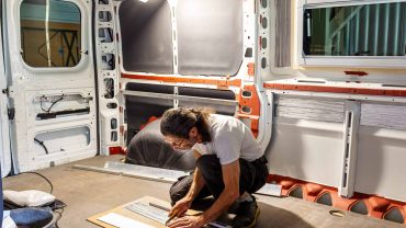 Van conversion insulation installation in a camper van interior.
