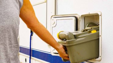 Person emptying waste from RV holding grey water tank.