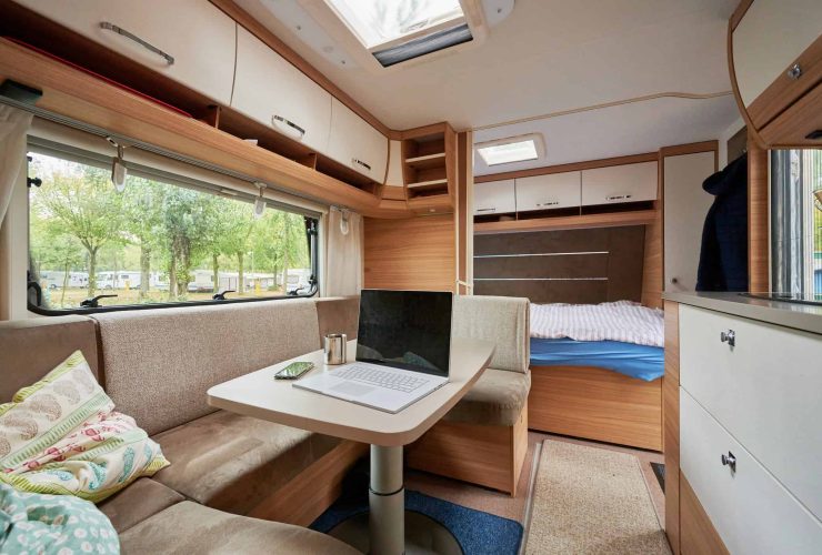 Compact camper interior with a cozy lounge, bed, and large windows for natural light. Perfect for tr.