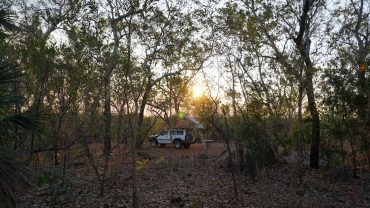 Camping in the Australian bush at sunset with a vehicle and tent.