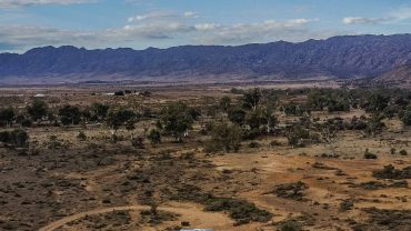 Caravan and car traveling through the Australian outback landscape.