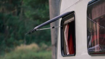 Caravan with open window in a scenic outdoor setting.