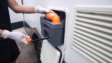Portable RV waste disposal system with orange pipe and gloves.