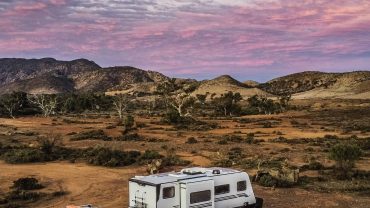 Outdoor camping scene with a caravan and truck in a rugged landscape.
