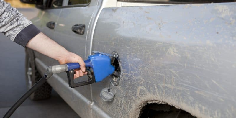 Person cleaning a muddy car with a pressure washer.