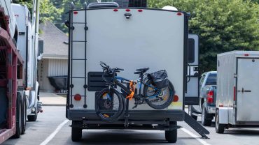 RV with mounted bicycle in a parking lot.