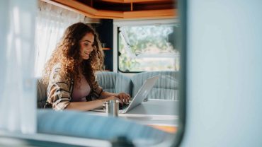 Woman using laptop inside campervan.